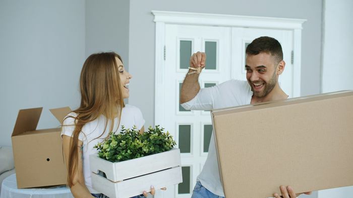 זוג צעיר ושמח בדירה החדשה שלהם, עם צרור מפתחות וארגזי מעבר
